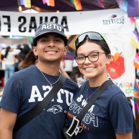 A female and male Latinx student smiling wearing 世界杯官方app gear